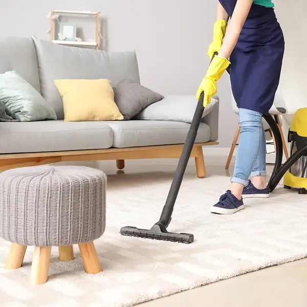 Aspiration du tapis d'un salon lors d'un ménage à domicile